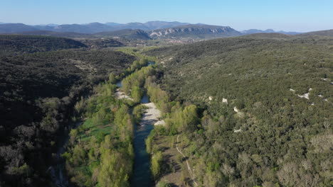 beautiful herault river with green tall trees and cevennes national park in back