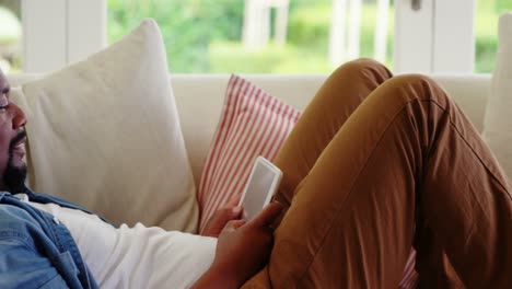 Man-lying-on-sofa-and-digital-tablet-in-living-room
