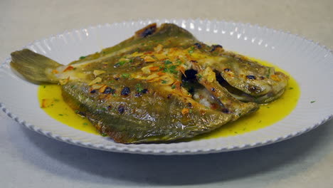 grilled turbot with garlic and butter sauce, lemon and aromatic herbs