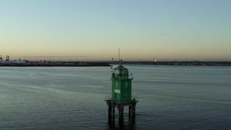 aerial orbit around green lighthouse in dublin port, ireland at sunset