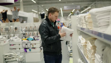 Young-man-chooses-towels-in-the-shop