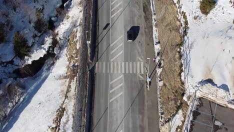 Overhead-view-of-vehicles-driving-on-a-snowy-road