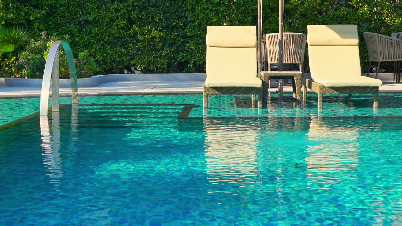 Liegestühle am Pool an einem wunderschönen blauen Swimmingpool.
