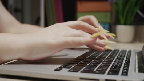 Frau-Mit-Langen-Gelben-Nägeln-Tippt-Auf-Der-Laptoptastatur