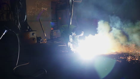 worker performing welding operation in dark industrial setting