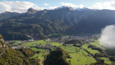 tomada aérea de derecha a izquierda de un valle con asentamientos en racimo rodeados de altas cumbres montañosas