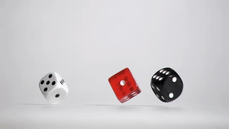 three white red black dices in a super slow motion rebonding