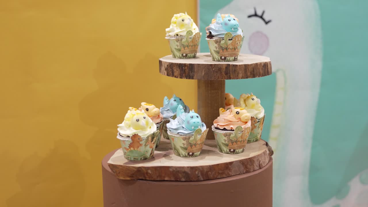 Colorful cupcakes decorated as cute animals displayed on a rustic stand
