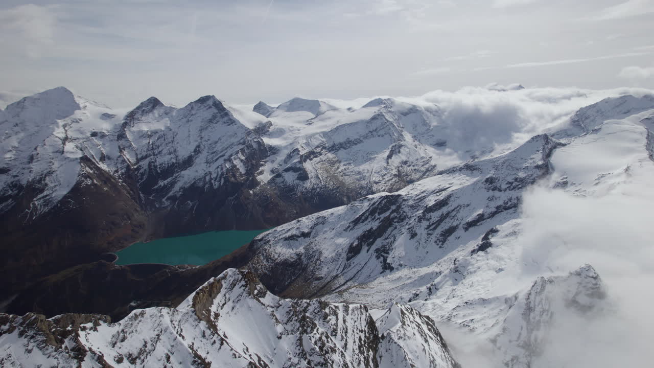 vuelo de drones que muestra la hermosa iluminación panorámica de la montaña nevada por el sol y el lago verde en el valle