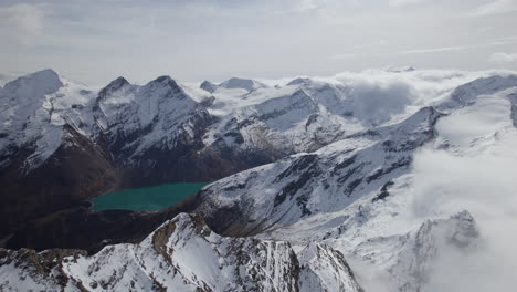 vuelo de drones que muestra la hermosa iluminación panorámica de la montaña nevada por el sol y el lago verde en el valle