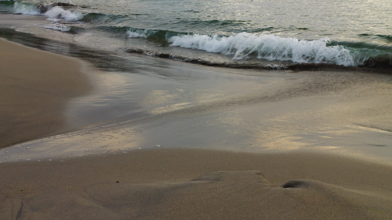 Medium shot of waves crashing into the sand beach in Norway