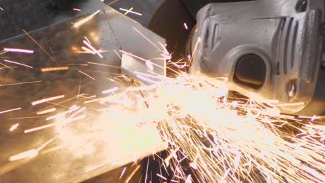 impressive spark shower of angular metal cutting. a metal worker is cleaning the rusty surface of a steel sheet. slow motion