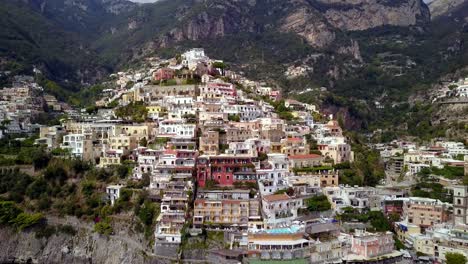 town of positano in the italian amalfi coastline showing hillside mansions and hotels in a colorful arrangement, aerial pedestal lift reveal shot