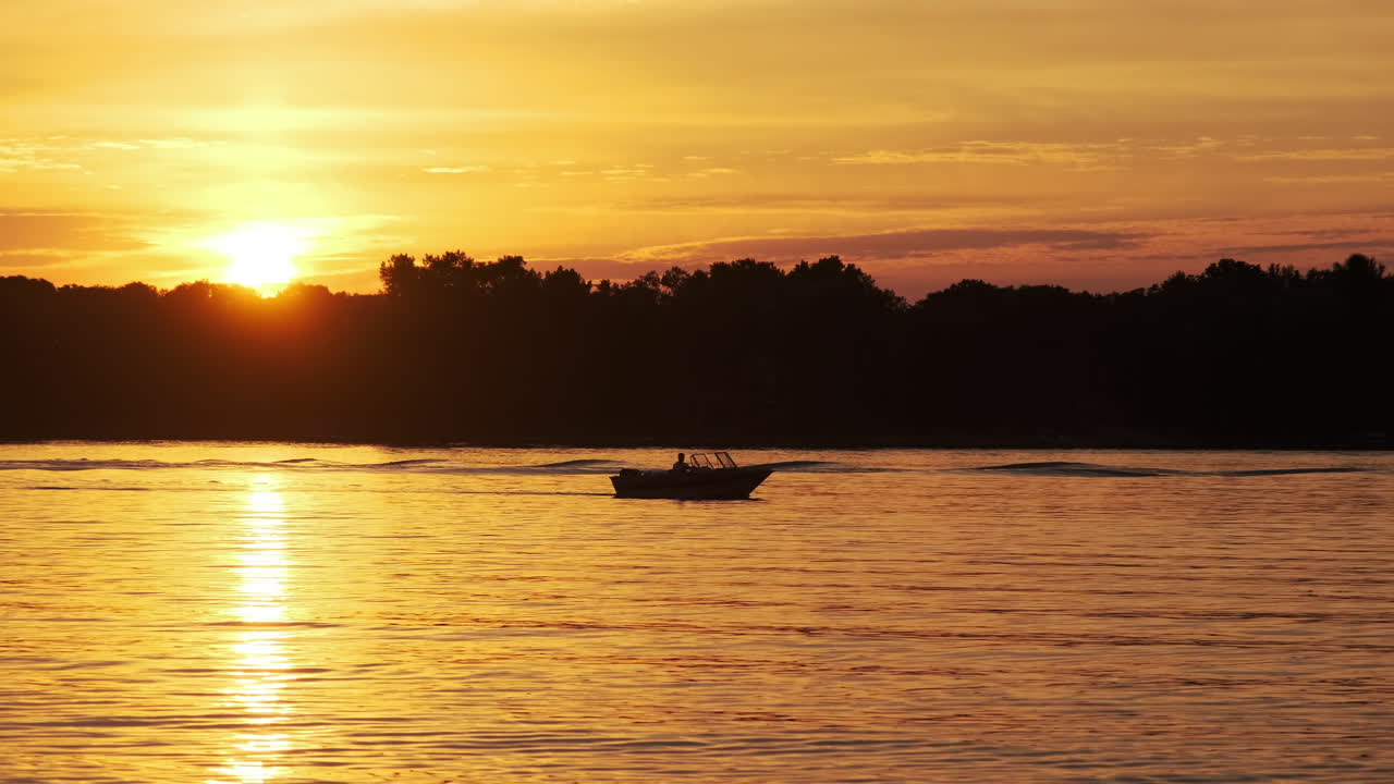 Speed boat silhouette with a beautiful sunset reflecting on calm water