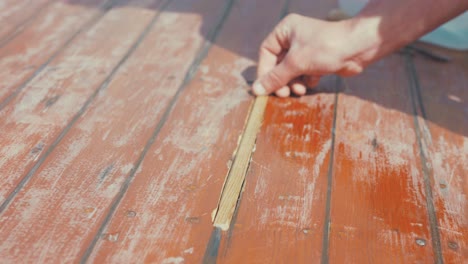 fitting wooden spline insert into wooden boat roof planking rubbing hand across, slow motion