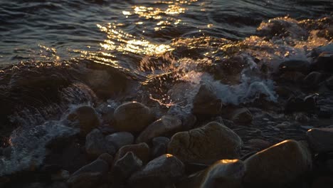 ocean water waves crashing on a rocky shoreline at sunset on rocks on the coastline