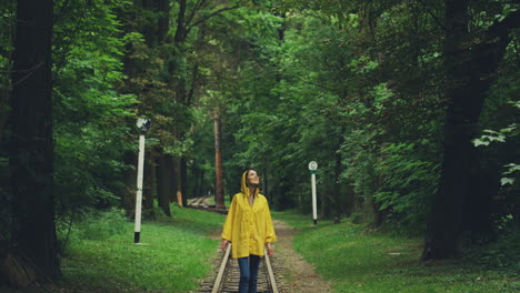 ragazza sorridente in un impermeabile giallo che cammina nel parco