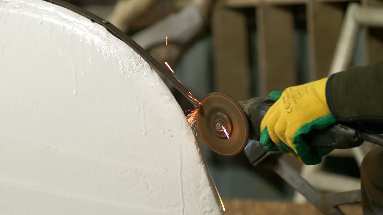 Smerigliatura del bordo di acciaio tagliato per la fascia della chiglia di una barca, utilizzando un disco per smerigliatrice angolare.
