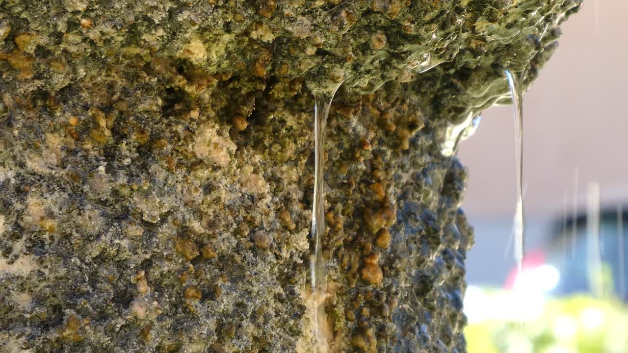 cerrar detalle de un lado de una antigua fuente de piedra y agua cayendo