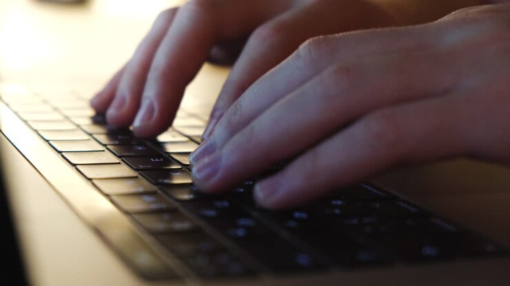 Close-up of hands typing on a laptop keyboard