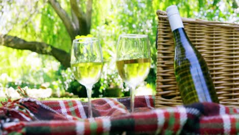 vasos de vino, botella y canasta de comida en la mesa