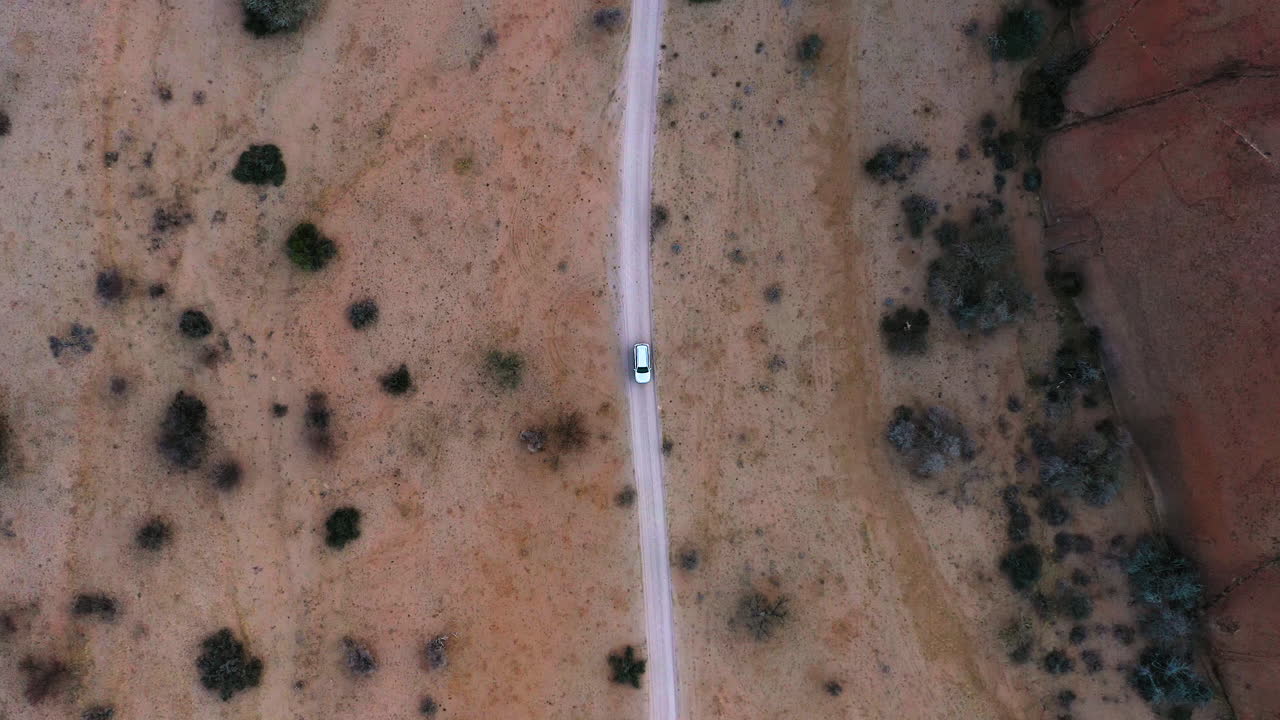SUV vehicle stopped on a wasteland road, evening in Africa - Rotating, Birds eye, drone shot