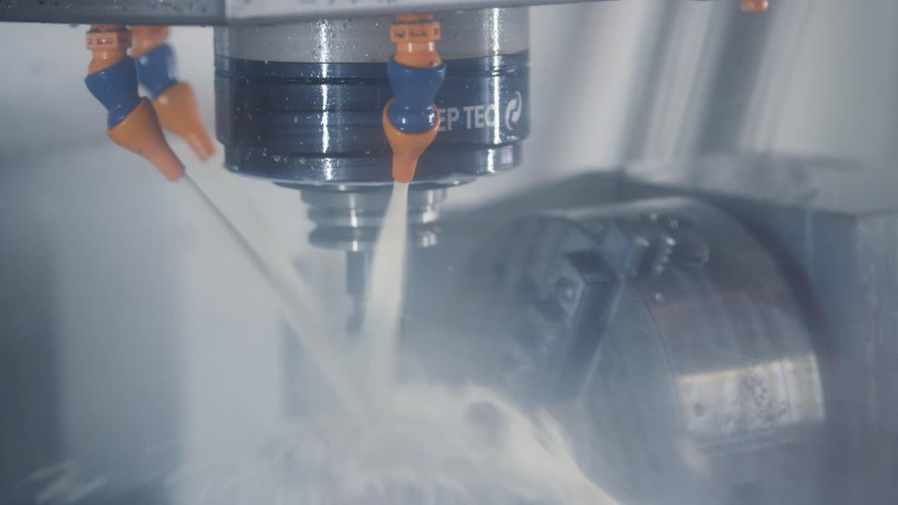 A milling machine processing raw metal parts with the use of coolants