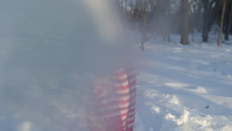 Child-girl-throwing-snowball-into-camera,-smiling-kid-walking,-playing-with-snow-in-winter-park