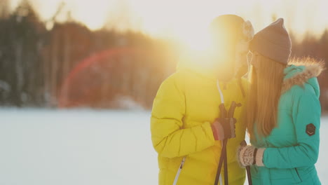 in the winter forest at sunset loving couple skiing and look around at the beauty of nature and attractions in slow motion.