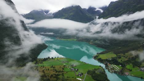 oldevatnet glacier lake and mountain valley covered in clouds in norway, loen, vestland - aerial circling