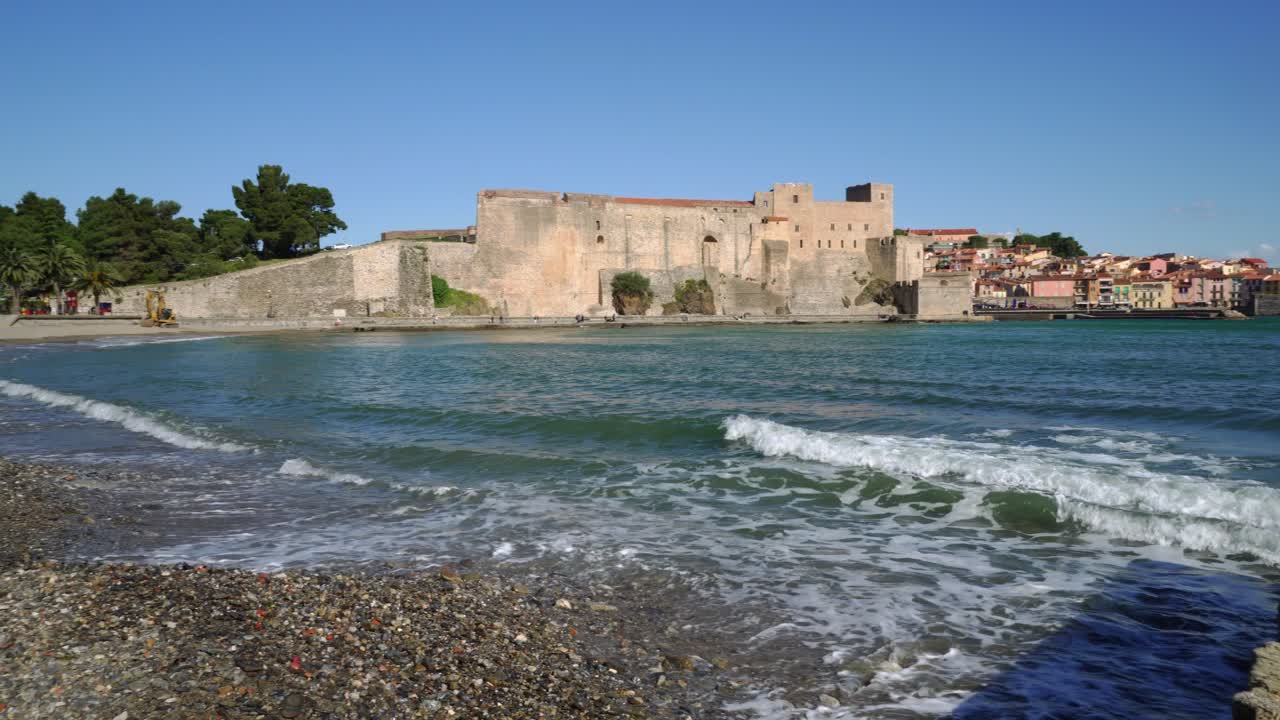 Lenta panoramica che mostra la storica città di Collioure e la sua spiaggia in una giornata ventosa