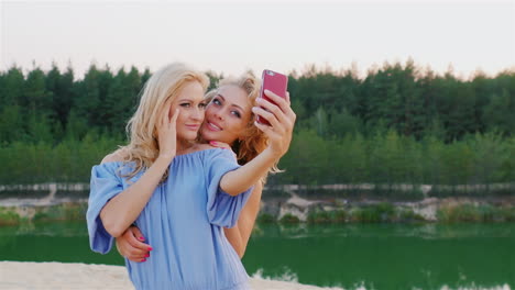 Zwei-Attraktive-Frauen-In-Kleidern-Machen-Selfie-Vor-Dem-Hintergrund-Der-Malerischen-Seen-Und-Wälder-S