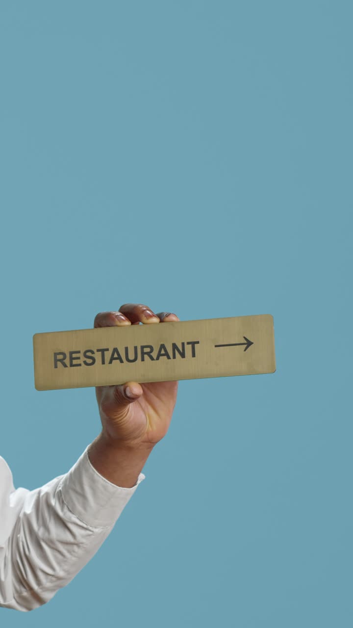 Mano che regge un cartello di un ristorante con freccia direzionale