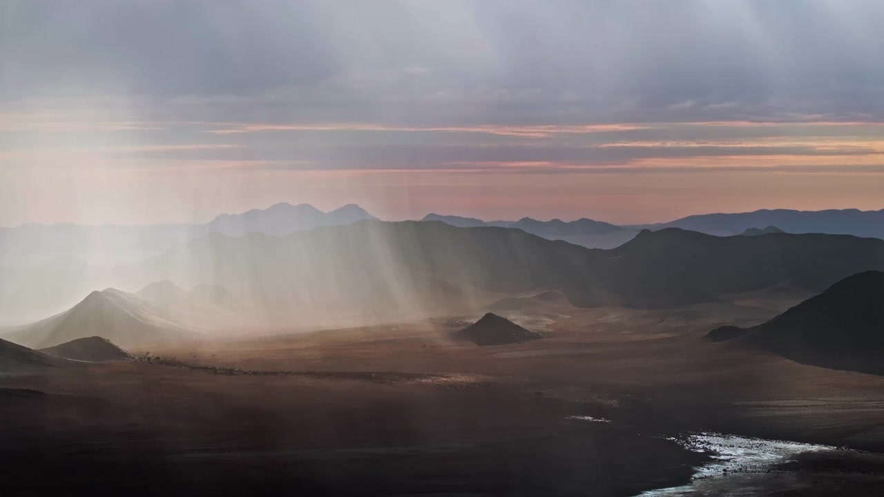 Vue aérienne par drone d'une pluie rare tombant sur le désert du Namib, créant un contraste saisissant entre des nuages sombres, du sable mouillé et de vastes paysages désertiques