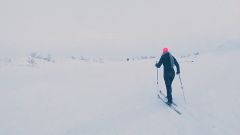 female cross country skier in a black body suit and pink beanie exercising alone