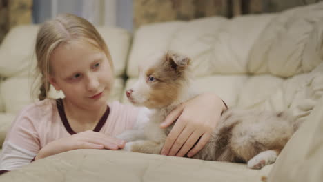 girl playing with a puppy on the couch in her house