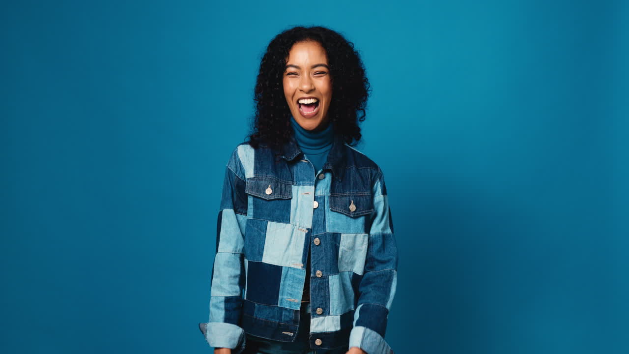 Woman laughing in denim jacket on blue background