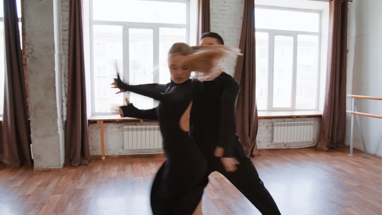A couple performing ballroom dancing in a spacious studio