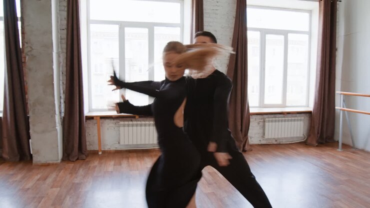 A couple performing ballroom dancing in a spacious studio