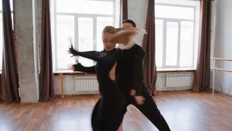 a couple performing ballroom dancing in a spacious studio
