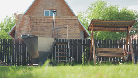 scenic backyard compound featuring wood fired hot tub with metal chimney and wooden deck steps, adjacent covered wooden swing bench, lush green lawn under clear sky