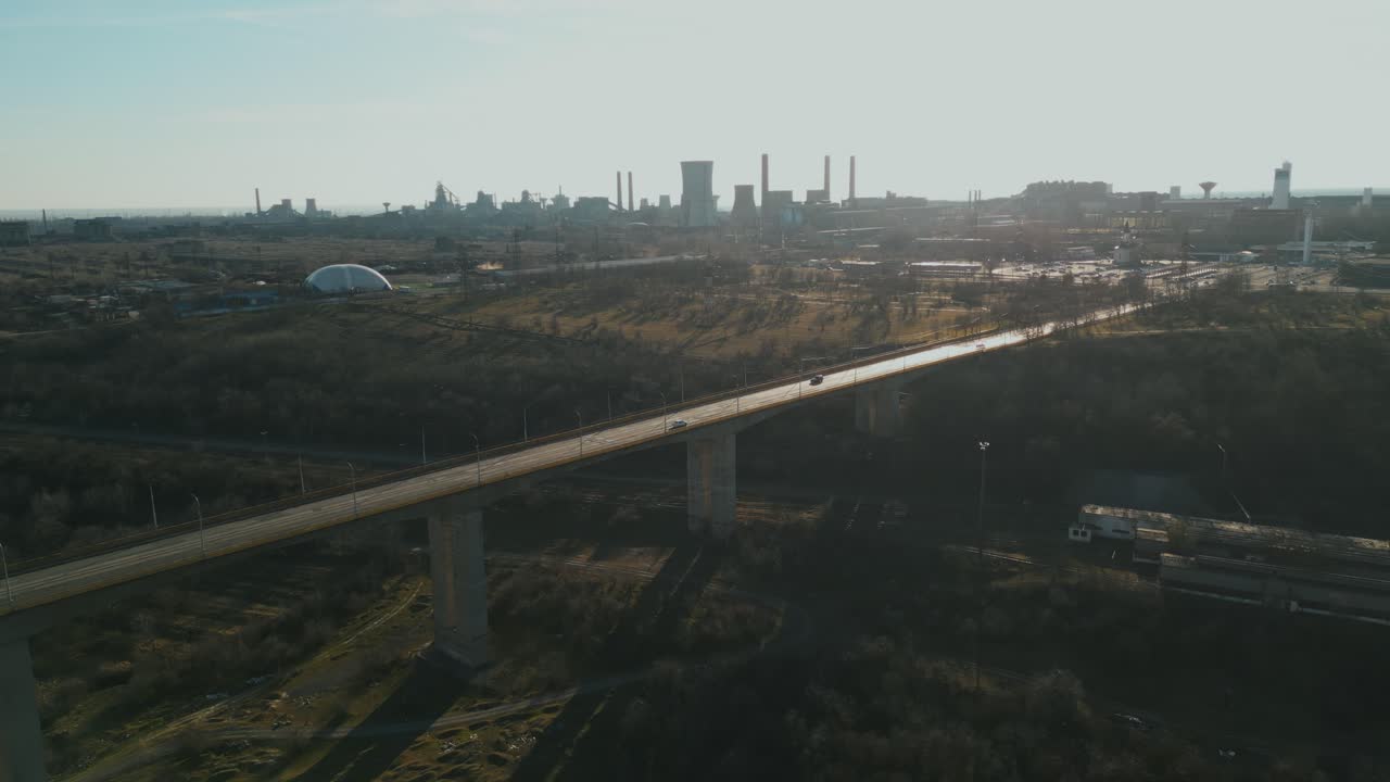 Vehicles Driving At Viaduct Bridge In Galati, Romania. Steel Manufacturing Plant In Background. wide drone shot
