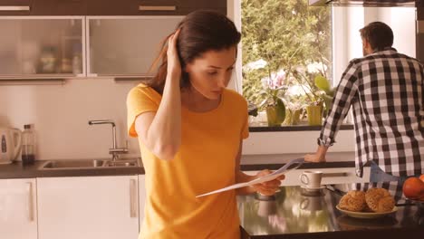 upset woman reading document while man looking out of window