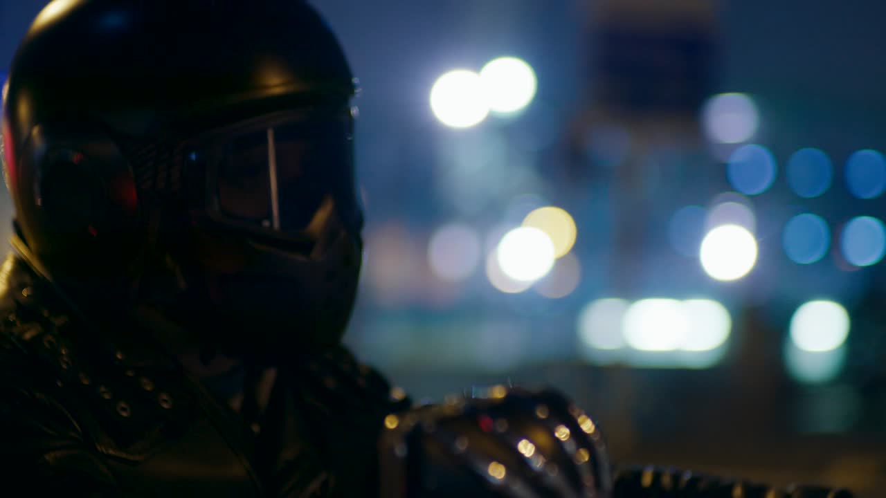 Primo piano di motociclista con casco che guida una moto in città con le luci notturne