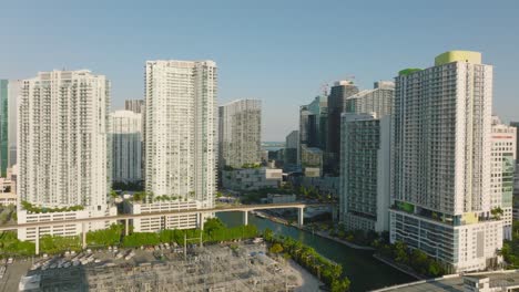 fly above city. heading towards modern complex of high rise apartment buildings along river. golden hour scene. miami, usa