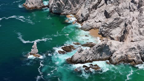 drone shot of pacific ocean waves breaking on rocky coast of cabo san lucas, baja california, mexico