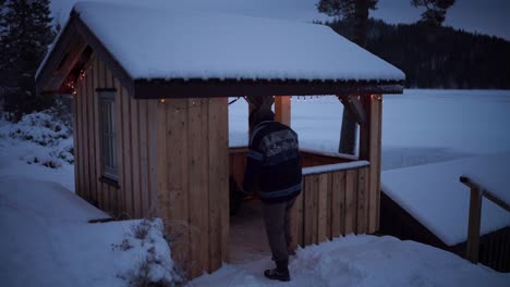 a man is making his way toward the wooden cottage on a winter day in indre fosen, trondelag county, norway - static shot