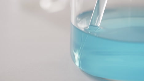 video of glass laboratory dish with blue liquid with copy space on white background