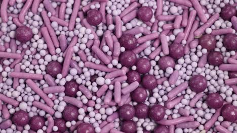 a spoon scoops vibrant purple candy sprinkles in a macro close-up, highlighting texture and color under bright lighting