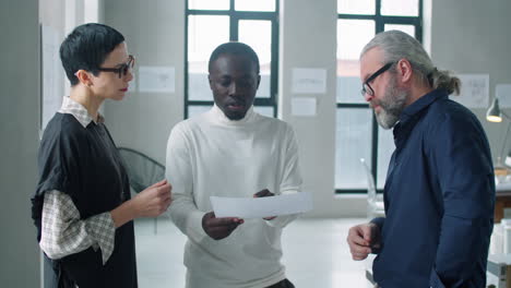 diverse multiage business team discussing business paper in office